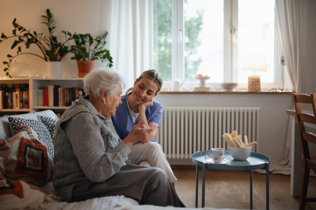 Older woman talking with a smiling companion in a bright living room.