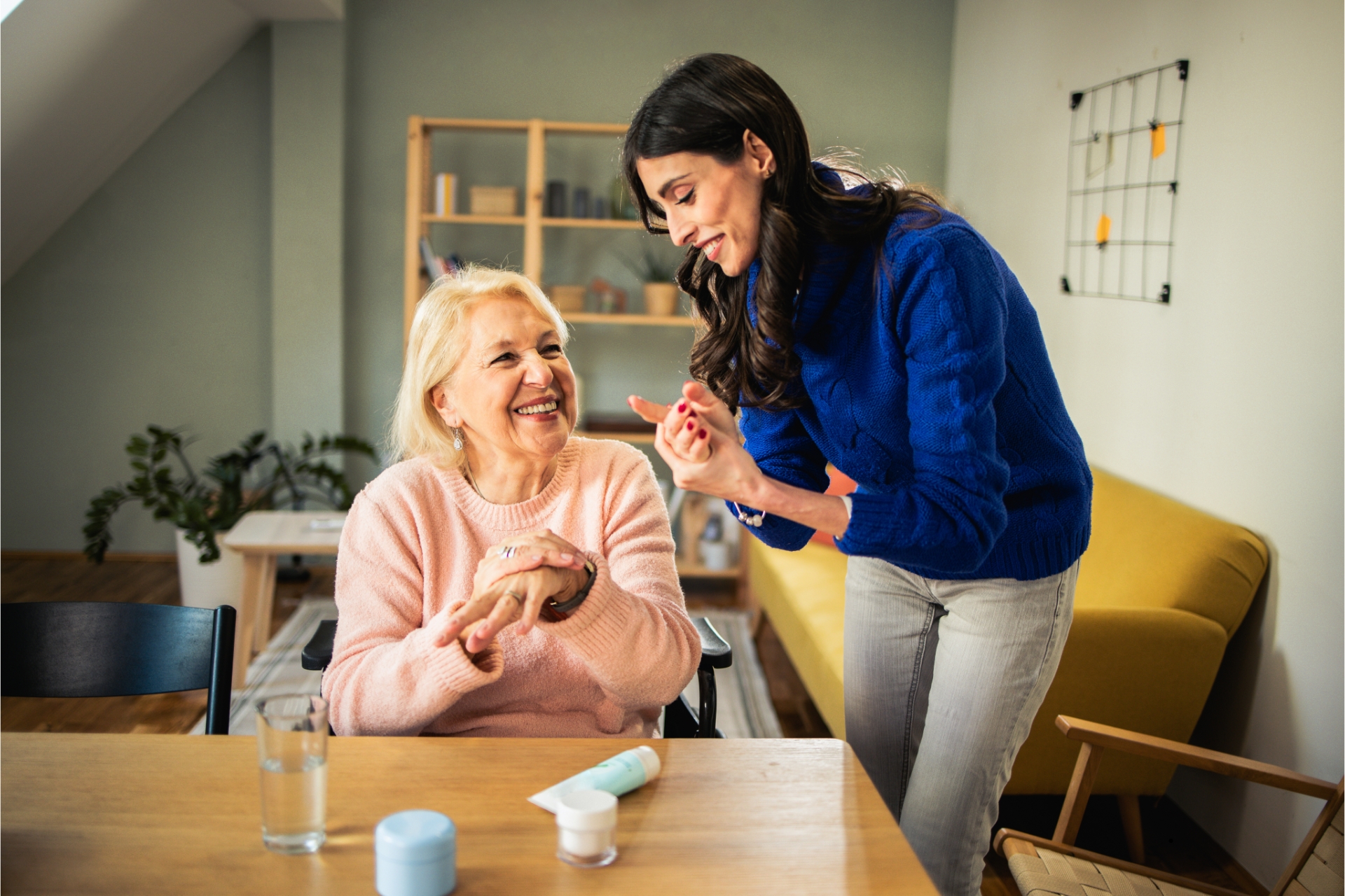 Older woman in a wheelchair laughing with a younger woman beside her.